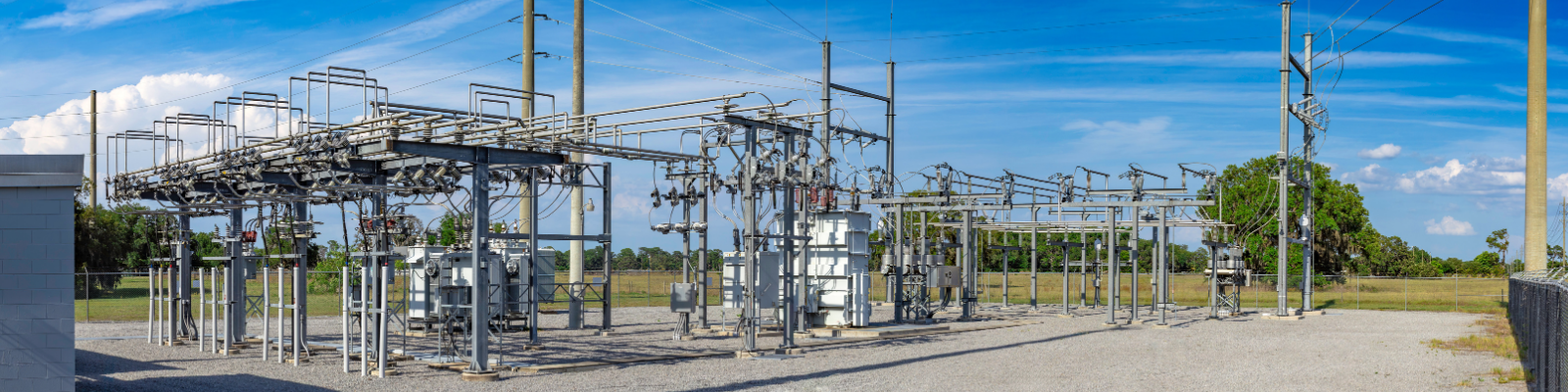 Electrical substation with transformers, switchgear, and transmission equipment under a blue sky.