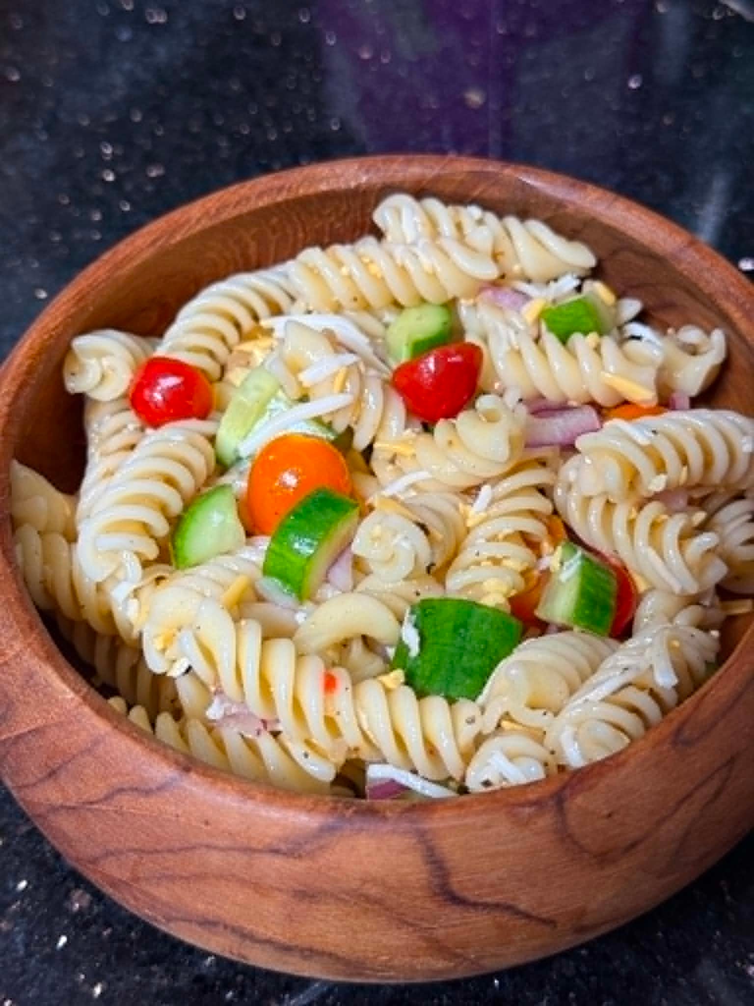Image of garden pasta salad recipe: Fusilli Pasta with diced cucumbers, tomatoes, red onion, and cheese.