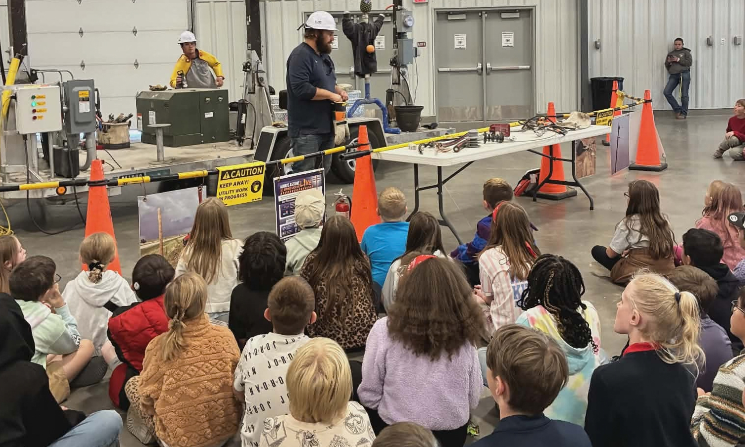 High West Energy personnel presenting a live electrical safety demonstration to a group of students inside a community facility.